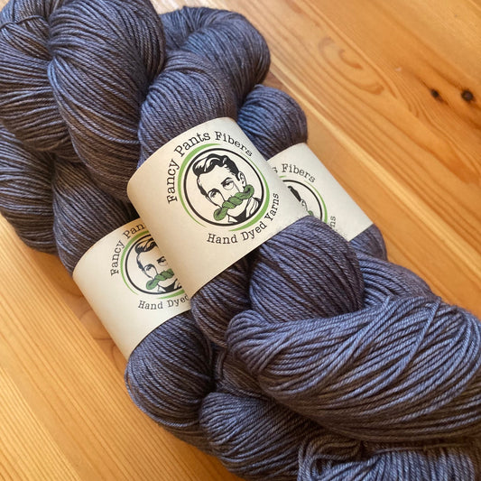 Slate colored yarn skeins with a label on a wooden surface